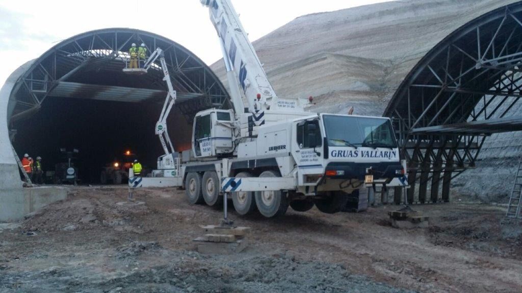 Un camión con una grúa acoplada está aparcado delante de un túnel.