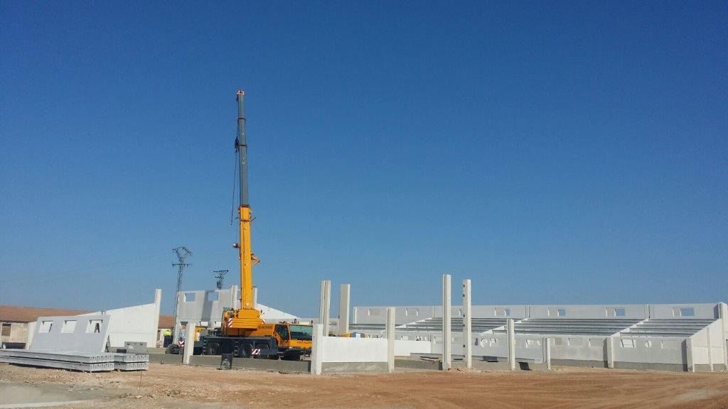 Una gran grúa amarilla está sentada frente a un edificio en construcción.