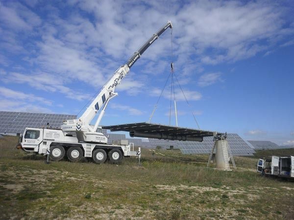 Una grúa grande está levantando una gran pieza de metal en un campo.