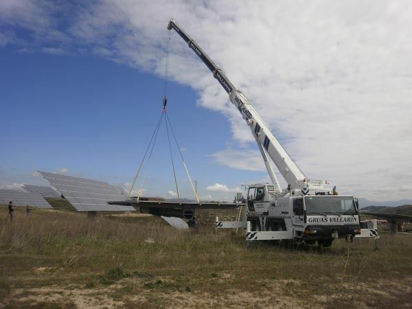 Una gran grúa está levantando un panel solar en un campo.
