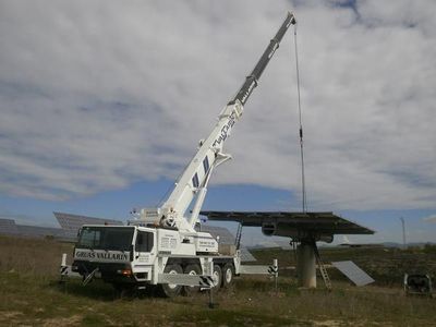 Una gran grúa está levantando un panel solar en un campo.