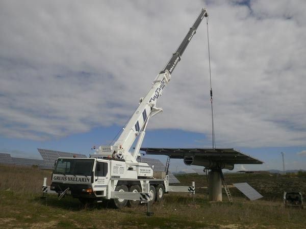 Una gran grúa está levantando un panel solar en un campo.