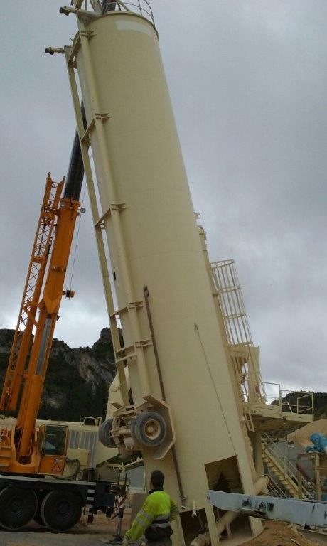 Un hombre está de pie junto a un gran cilindro blanco con una grúa en el fondo.