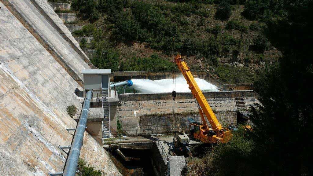 Una gran grúa amarilla está trabajando en una presa.