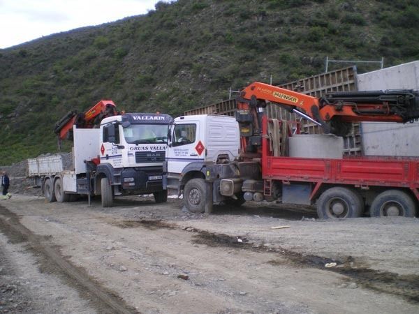 Dos camiones están estacionados uno al lado del otro en un camino de tierra.