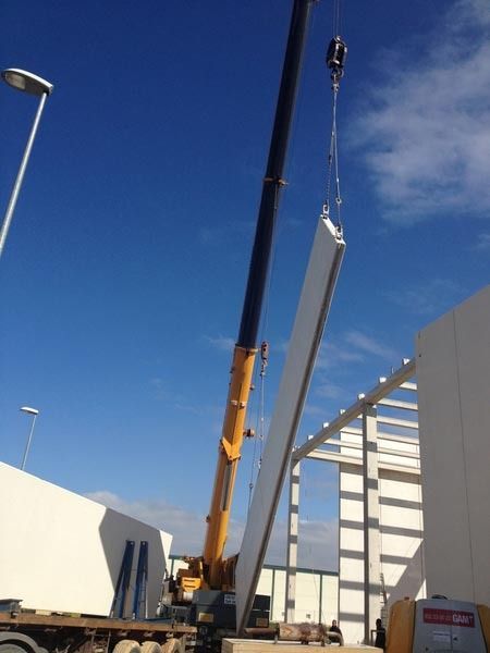 Una grúa está levantando un trozo de hormigón delante de un edificio.