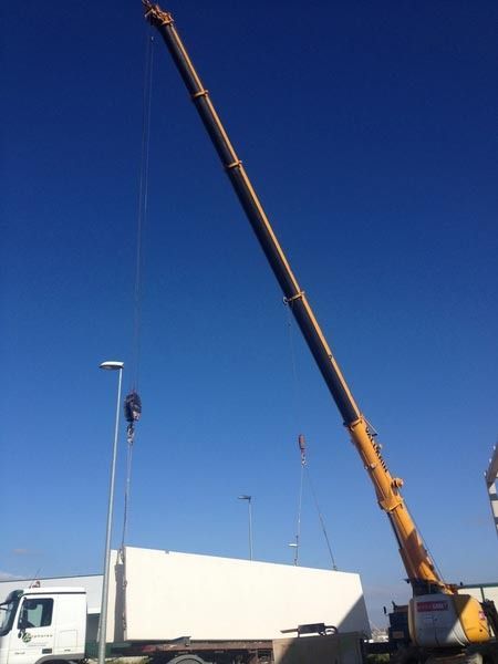 Una gran grúa amarilla está levantando una caja blanca