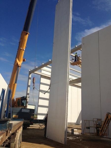Una grúa está levantando una gran pared blanca.
