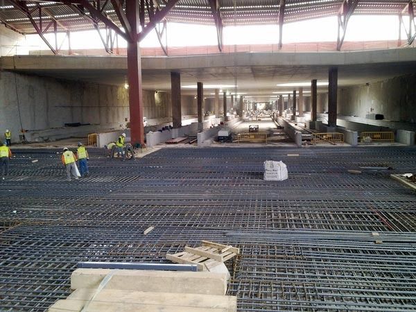 Un gran edificio en construcción con trabajadores en el suelo.