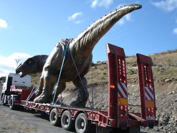 Una estatua de un dinosaurio está siendo transportada en un remolque.