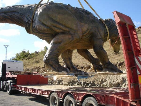 Una estatua de un dinosaurio está siendo levantada por una grúa.