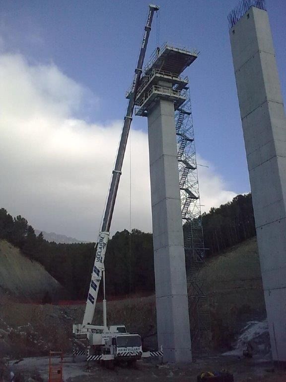 Una grúa está levantando una estructura de hormigón en la parte superior de una torre.