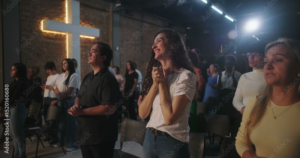 Menschen in einem Gottesdienst vor einem leuchtenden Kreuz. Einige haben die Hände gefaltet, andere blicken zum Licht.