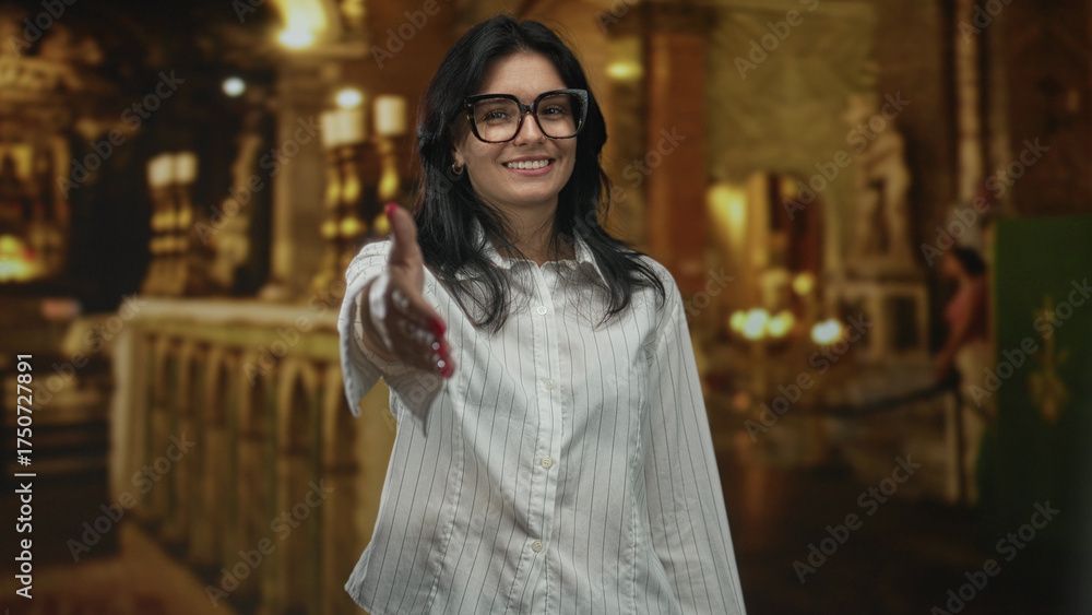 Eine Frau mit Brille streckt lächelnd in einer Kirche die Hand zum Händeschütteln aus.