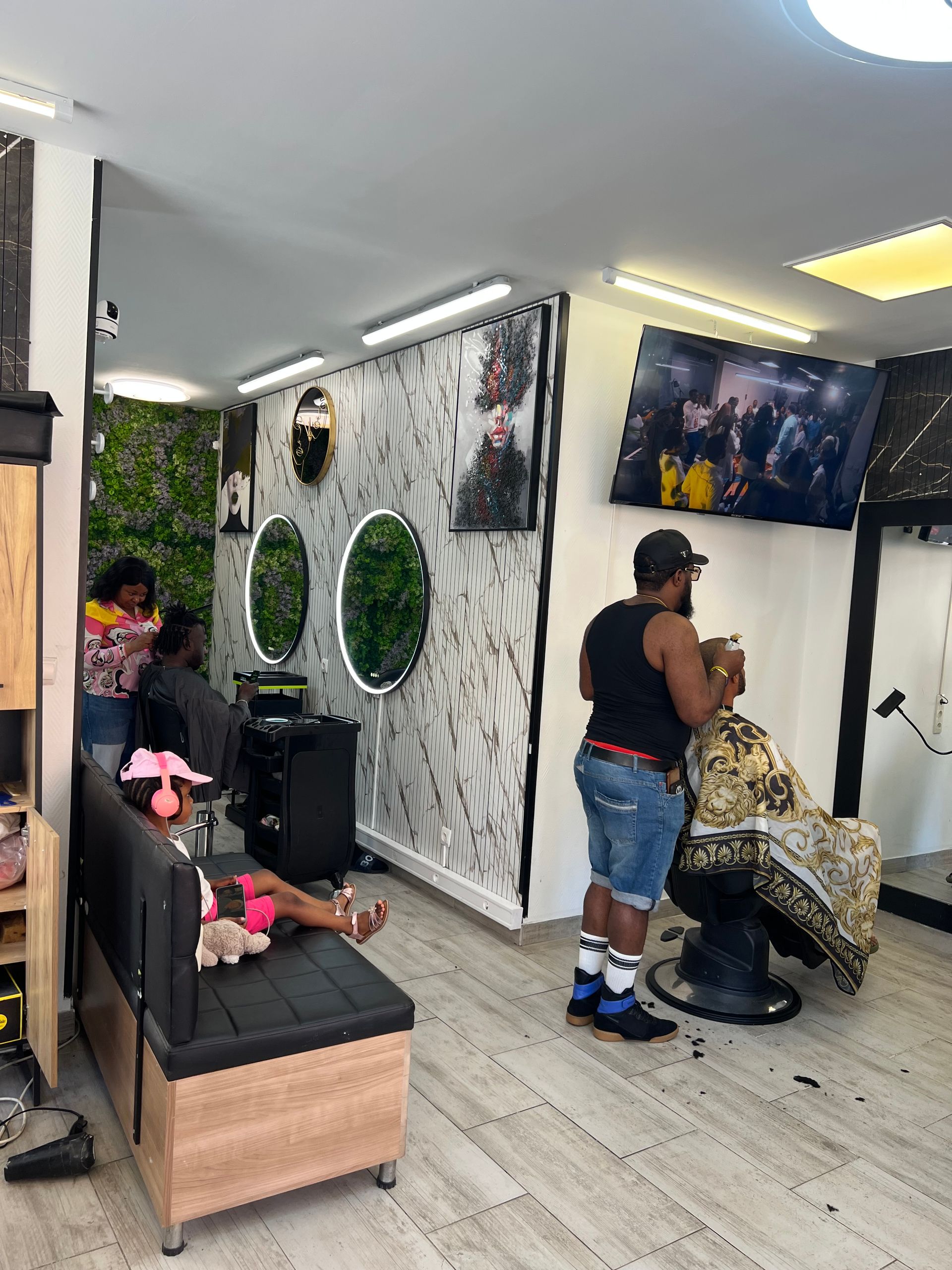 Intérieur d'un salon de coiffure avec une coiffeuse travaillant sur une cliente assise près des miroirs muraux et des fauteuils de salon
