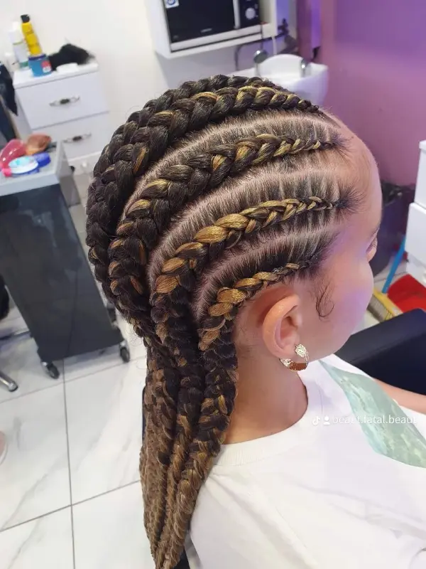 Tresses africaines tressées avec des accents dorés, coiffées sur un fauteuil de salon