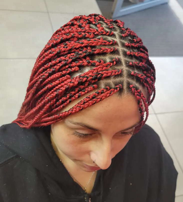 Vue de dessus d'une personne aux cheveux rouges tressés et à la raie au milieu, regardant vers le bas à l'intérieur.