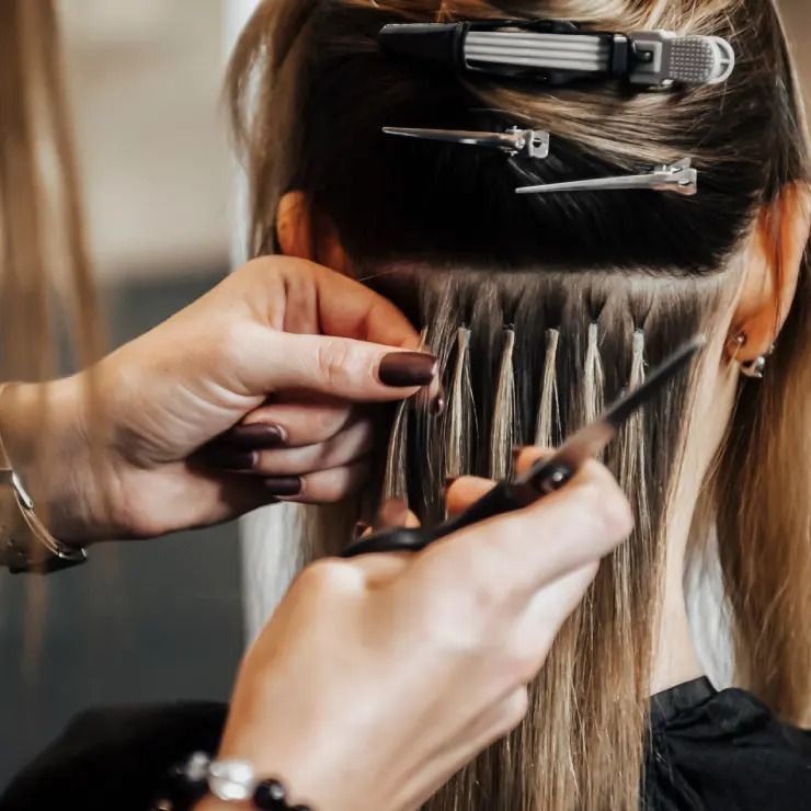Coiffeuse séparant les cheveux avec des pinces et un peigne lors d'un soin en salon