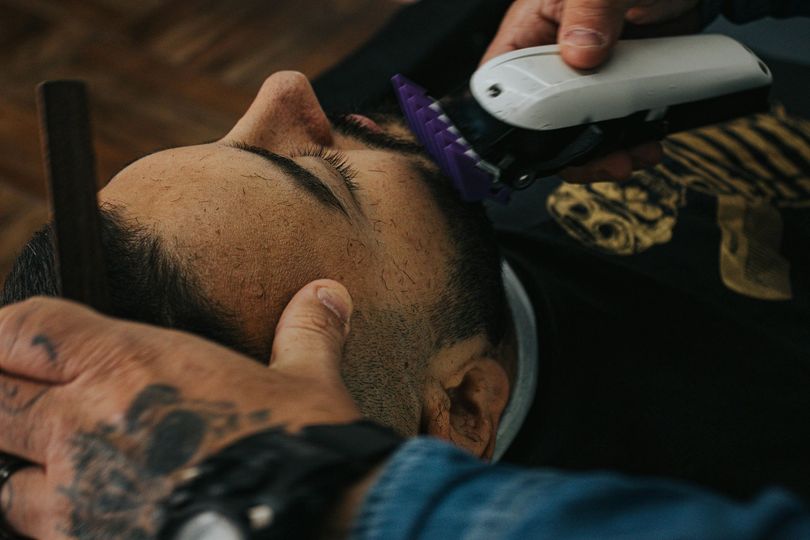 Gros plan sur un barbier taillant la barbe d'un homme avec une tondeuse électrique