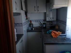 Cocina pequeña con gabinetes blancos, encimera oscura y protector contra salpicaduras de azulejos.