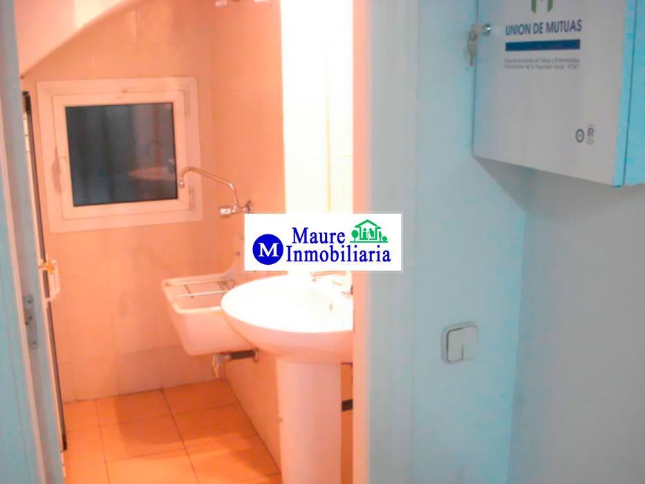 Baño pequeño con lavabo, inodoro, ventana y armario. Paredes blancas y naranja claro.