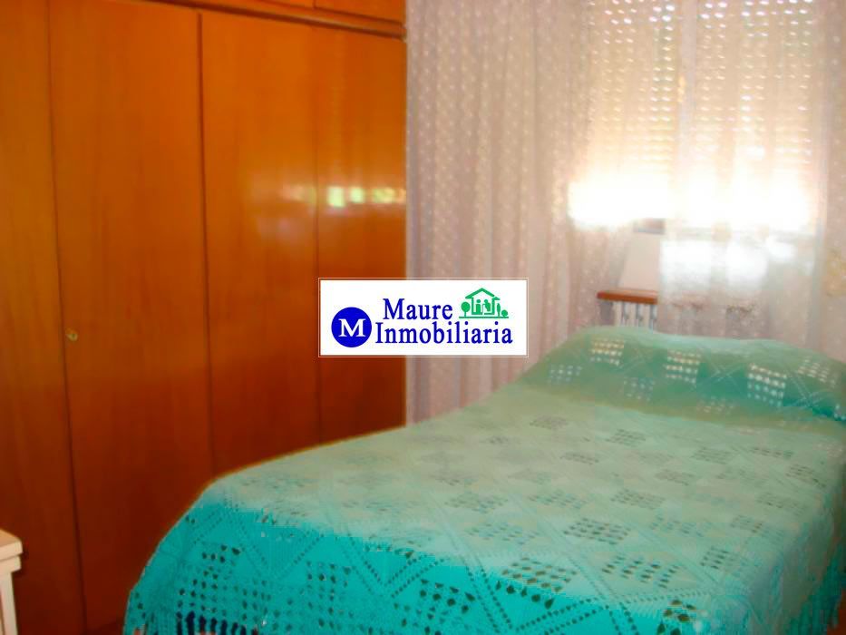 Dormitorio con armario de madera, cama cubierta con una colcha de crochet verde y una ventana cubierta con encaje.