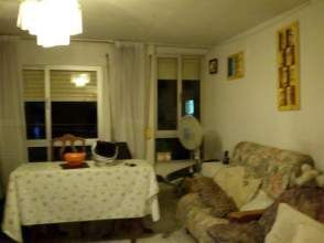 Sala de estar con mesa, sofá, ventilador y ventana. Iluminación tenue.