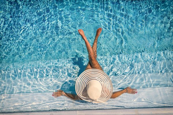 Personne allongée dans une piscine, les jambes croisées et les bras étendus.