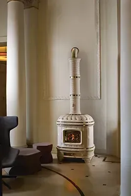 Una estufa blanca está sentada en una sala de estar al lado de una silla.