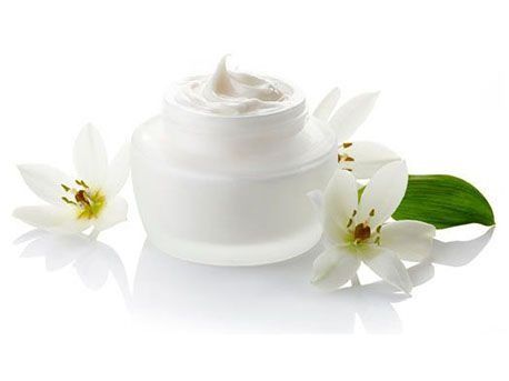 Un tarro de crema con flores blancas y hojas sobre un fondo blanco.