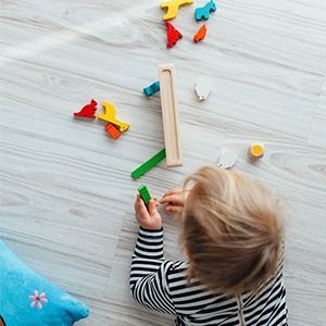 Una niña está jugando con juguetes de madera en el suelo.