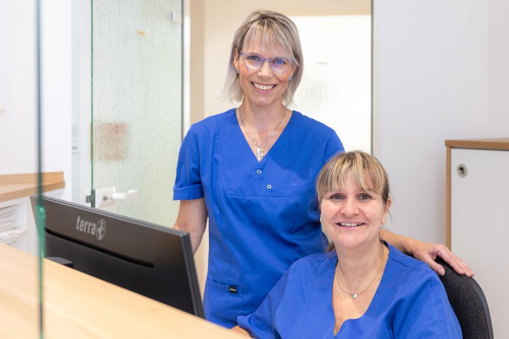 Eine Frau sitzt an einem Rezeptionstresen und telefoniert.