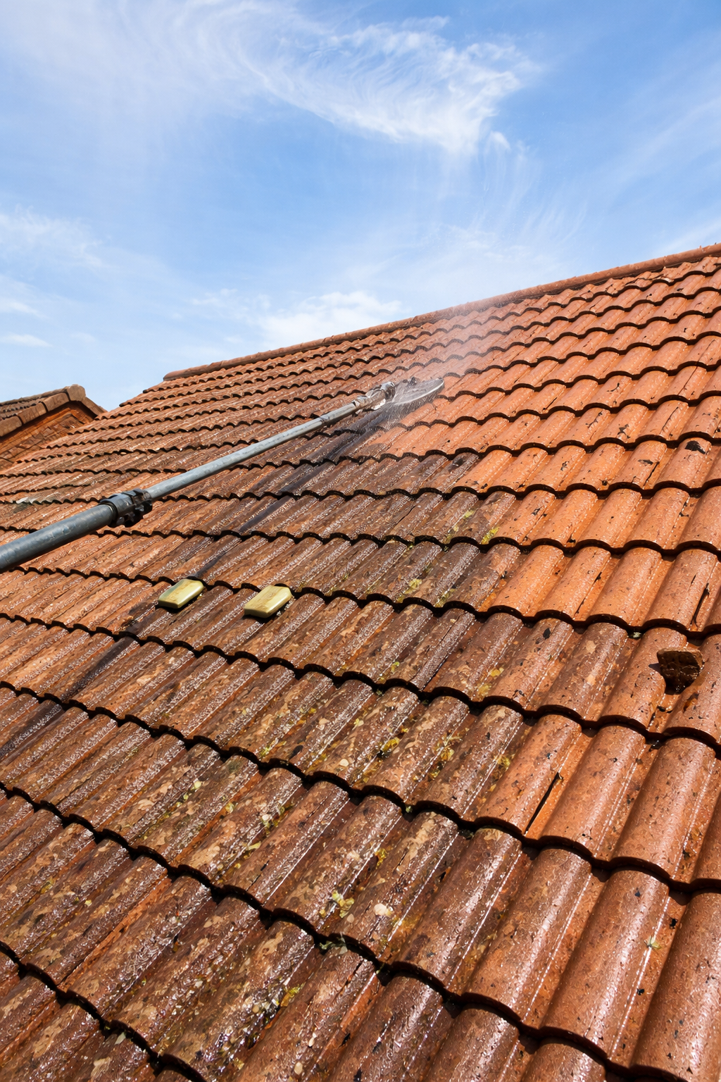 Red-tiled roof with black gutter pipes under a blue sky