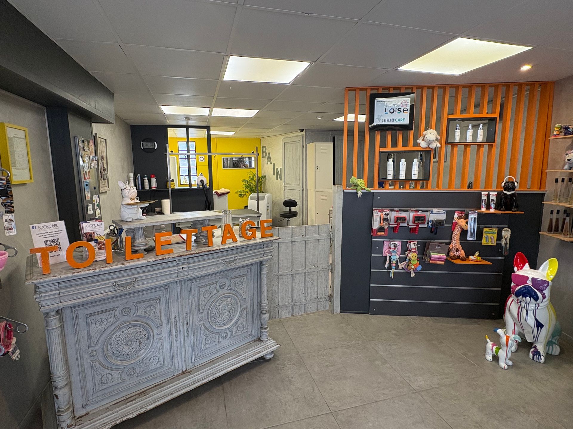 Comptoir de magasin de cadeaux et de jouets avec une enseigne orange, des étagères et une figurine de chien blanc près de l'entrée