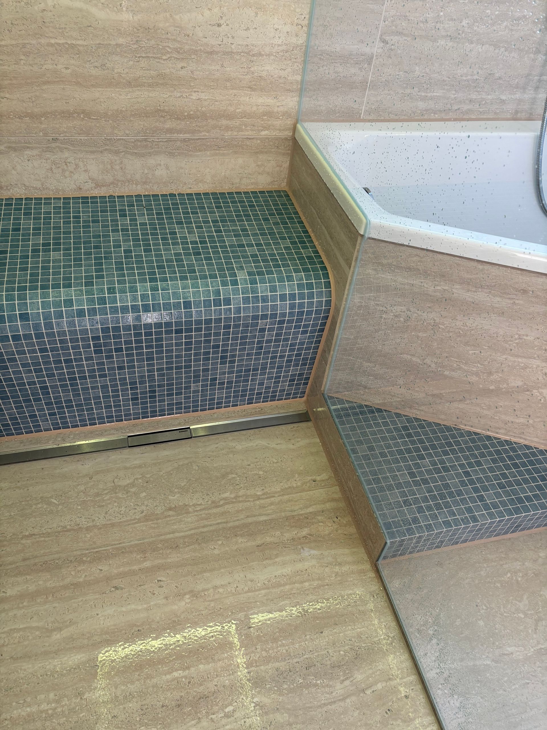 Innenausstattung aus Holz mit eingebauter weißer Badewanne und grün gemusterter Bank bzw. Trittstufe.