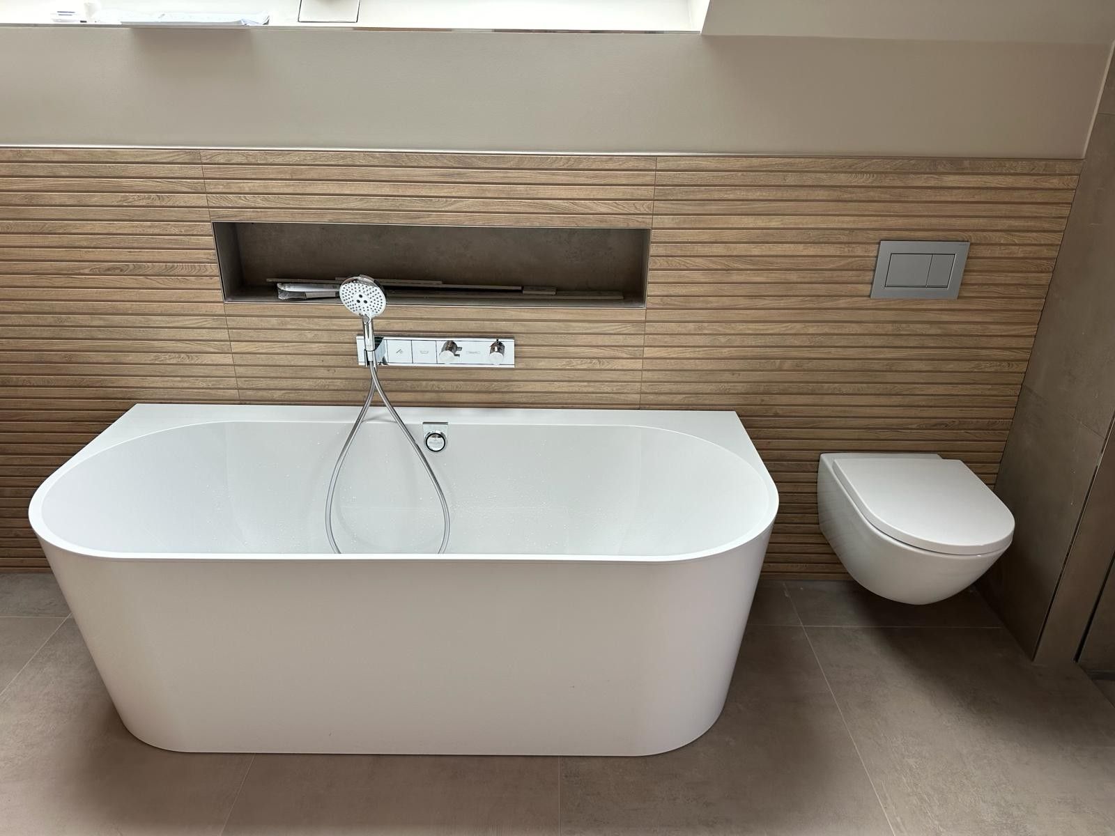 Modernes Badezimmer mit freistehender weißer Badewanne, Wandarmatur und kleinem Wandwaschbecken