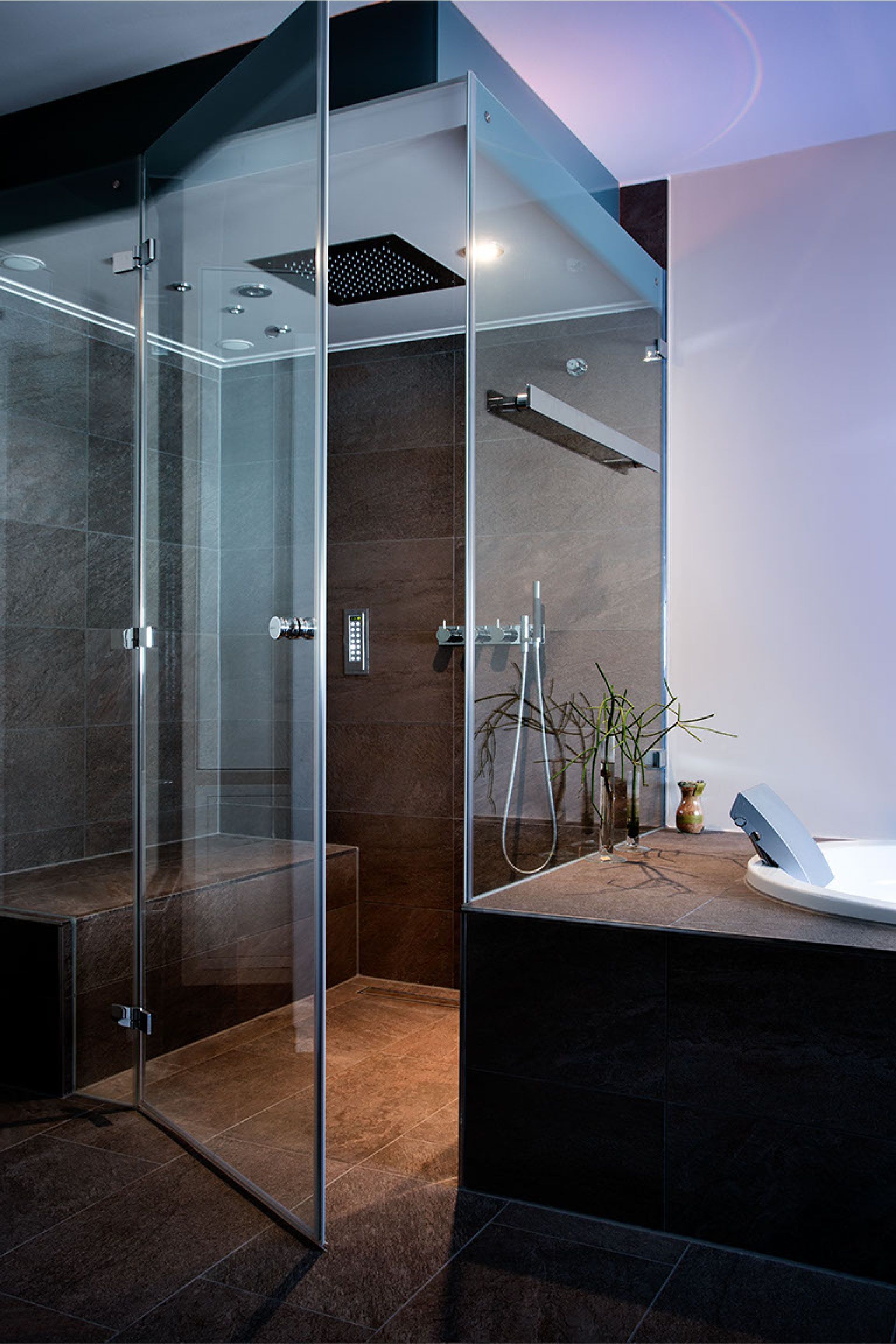 Moderne Glasduschkabine mit dunklen Fliesen, Kieselboden und Badewanne in einem eleganten Badezimmer