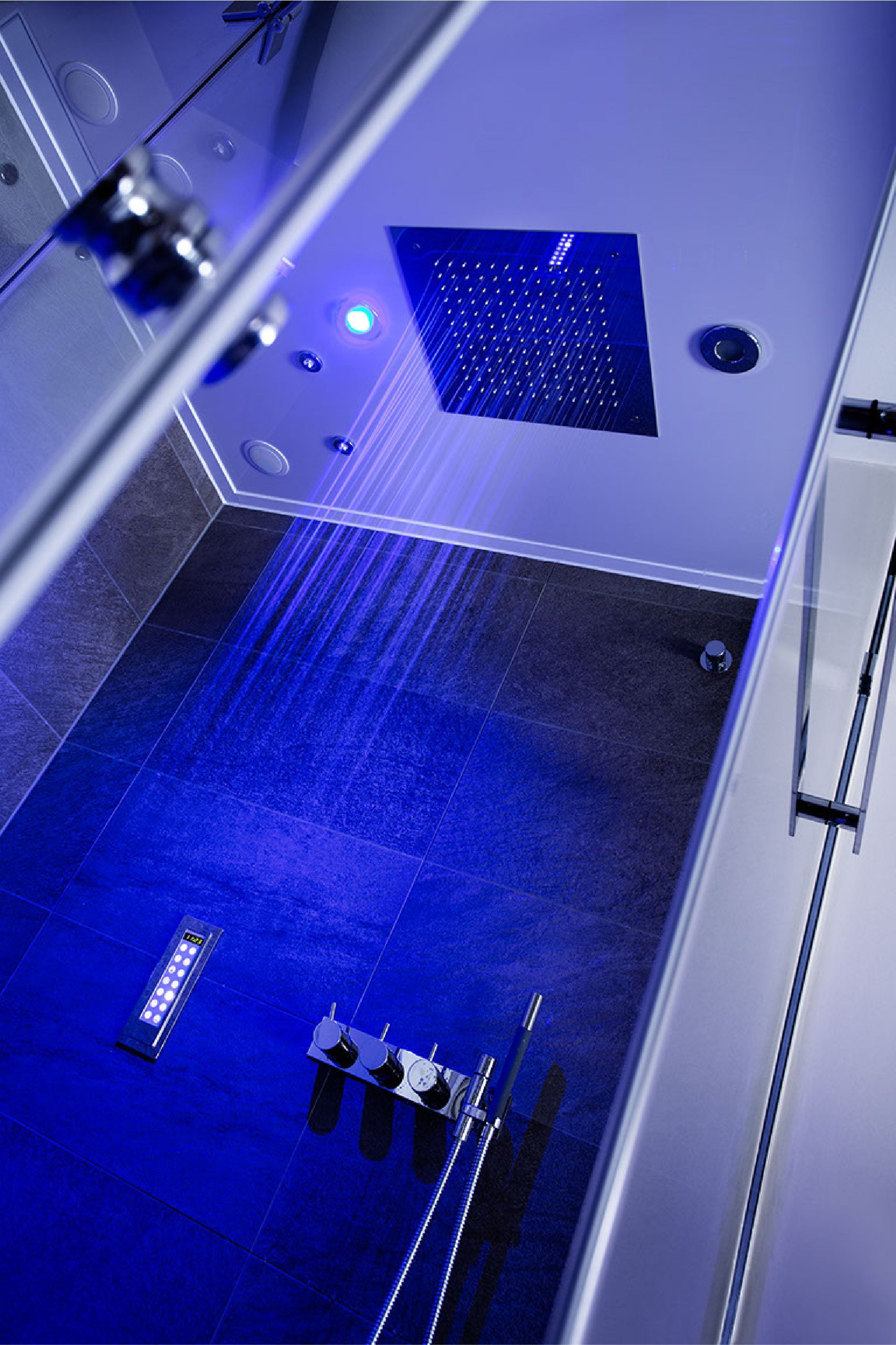 Blau beleuchteter Innenraum einer Industriemaschine mit perforierter Frontplatte und Metallteilen auf dem Boden.