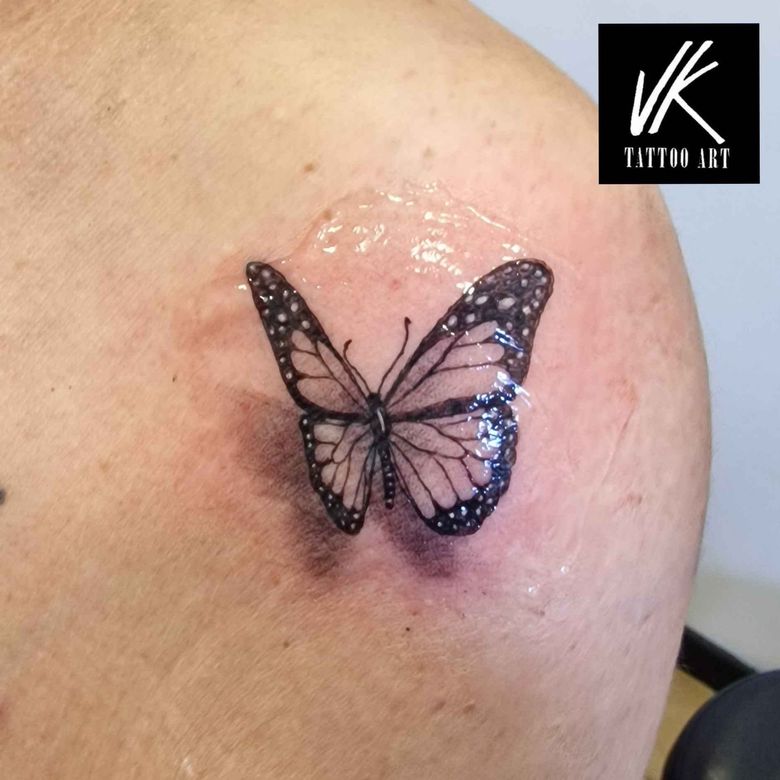 Un pequeño y detallado tatuaje de mariposa negra en el hombro.