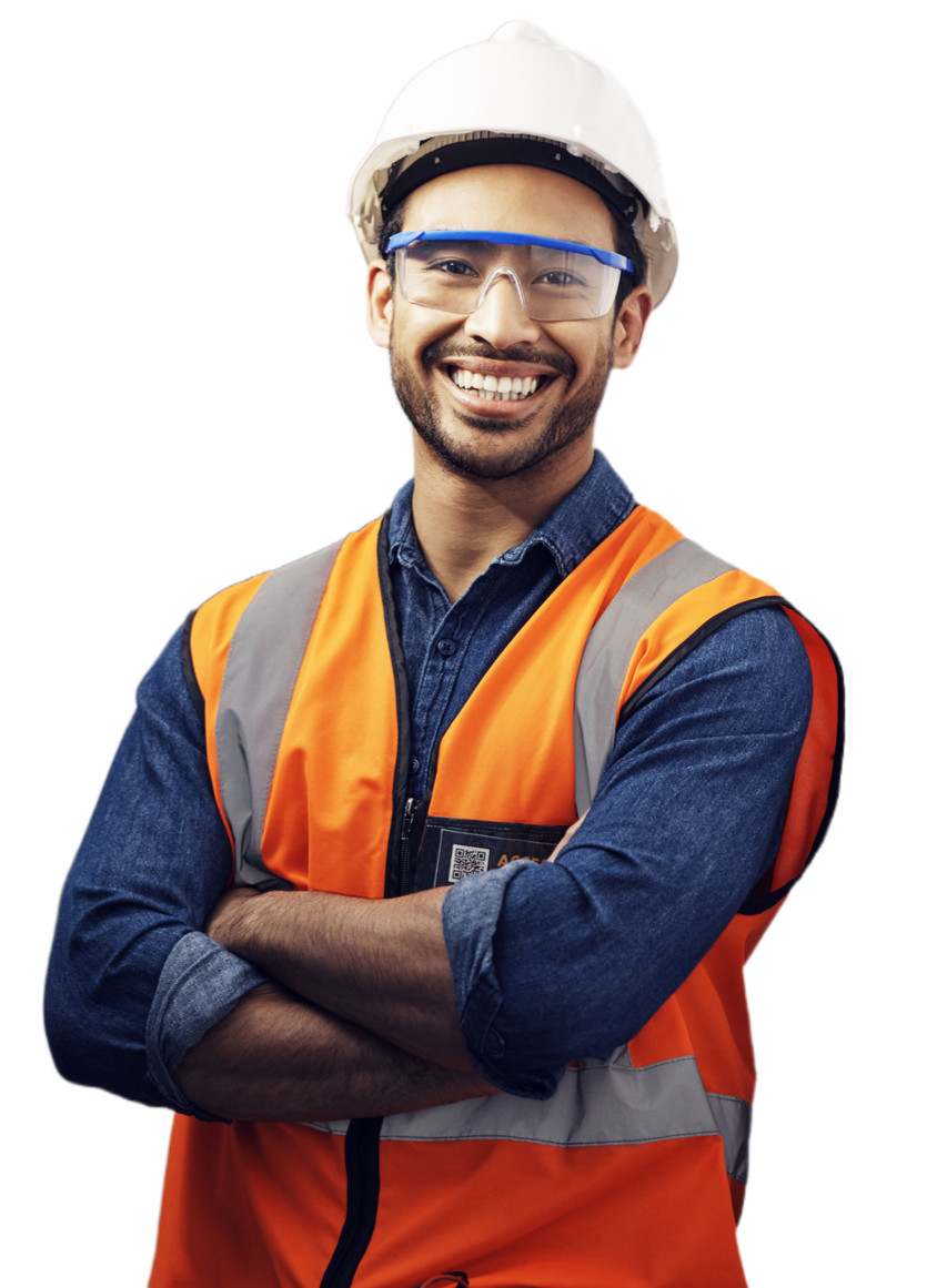 Un homme portant un casque, des lunettes de sécurité et un gilet de sécurité sourit, les bras croisés.