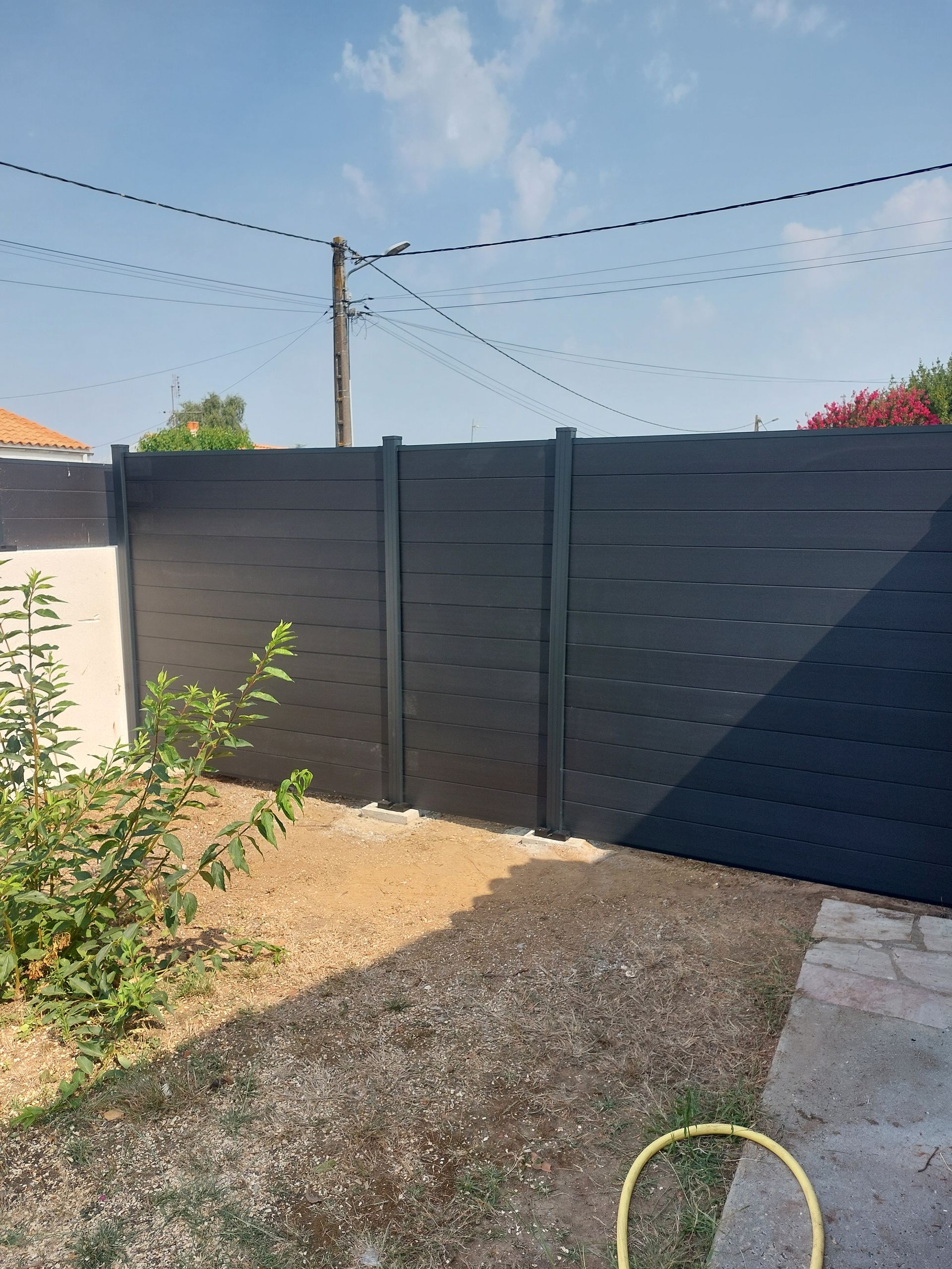 Une clôture moderne à lattes horizontales noires.