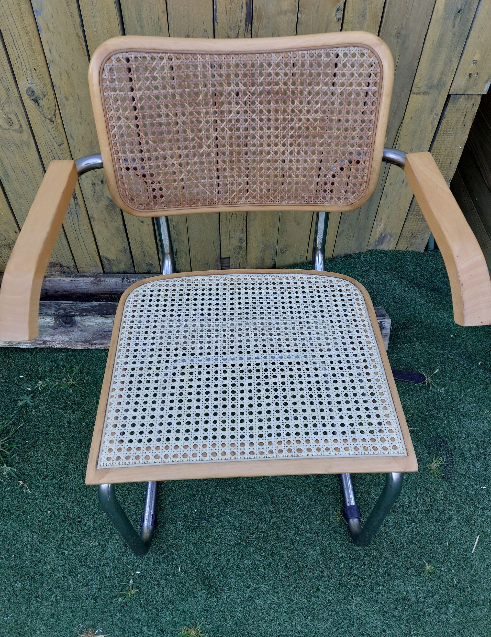 Une chaise vintage à structure chromée, avec dossier et assise en rotin garnis de bois.