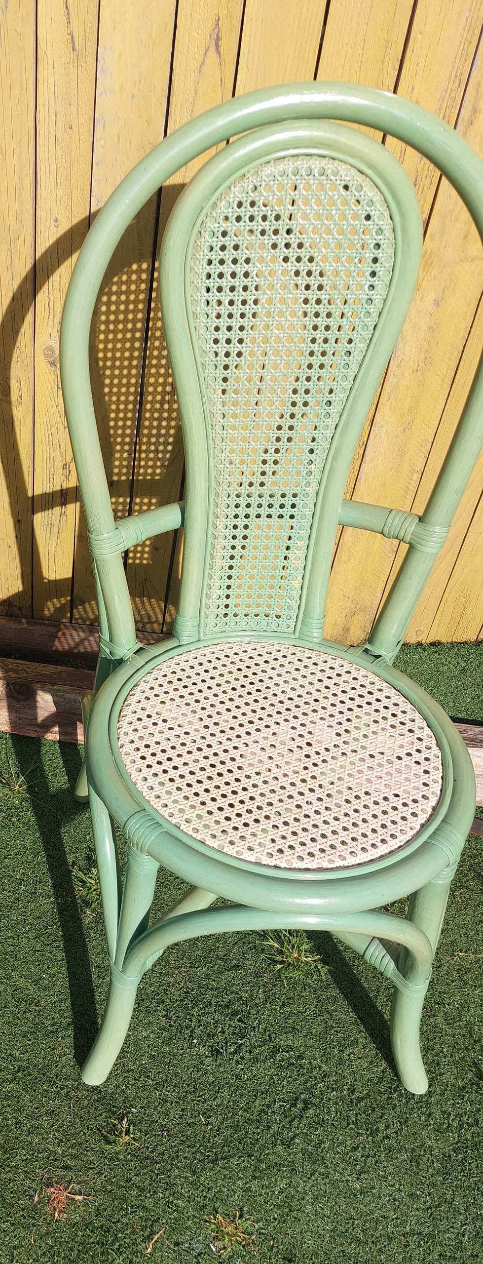 Un fauteuil en osier vert pâle à haut dossier et une assise neuve.