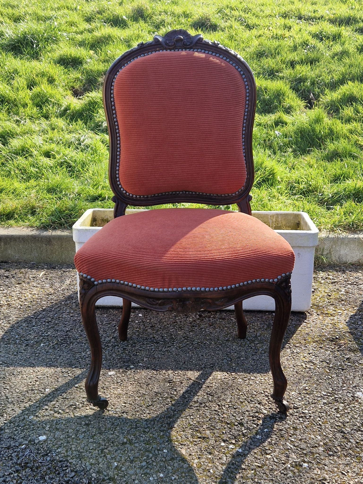 Une chaise d'extérieur de style vintage, en bois foncé, avec des pieds galbés et ornés.