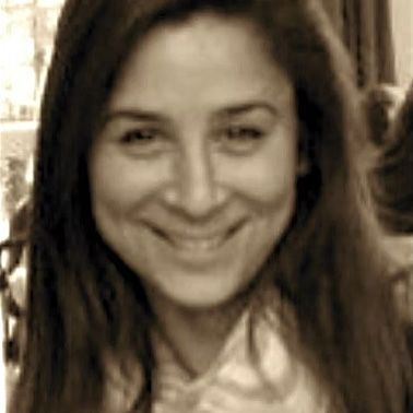 Lächelnde Frau mit langen, dunklen Haaren. Sie hat helle Haut und blickt den Betrachter an.