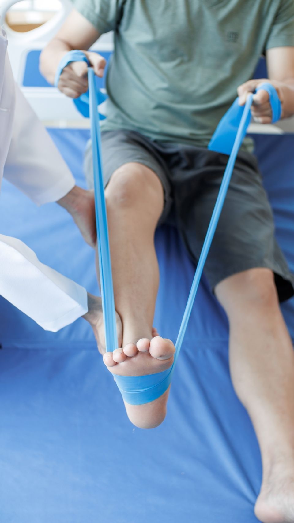 Eine Person streckt ihren Fuß mit einem blauen Gummiband. Johan Duchateau Praxis f. Physiotherapie - PROACTIVE