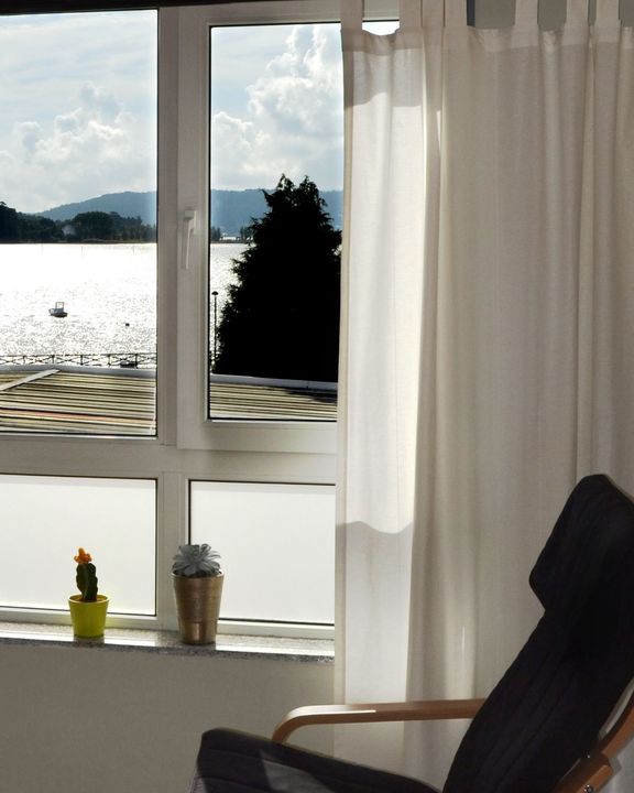 Una silla frente a una ventana con vista a un cuerpo de agua.