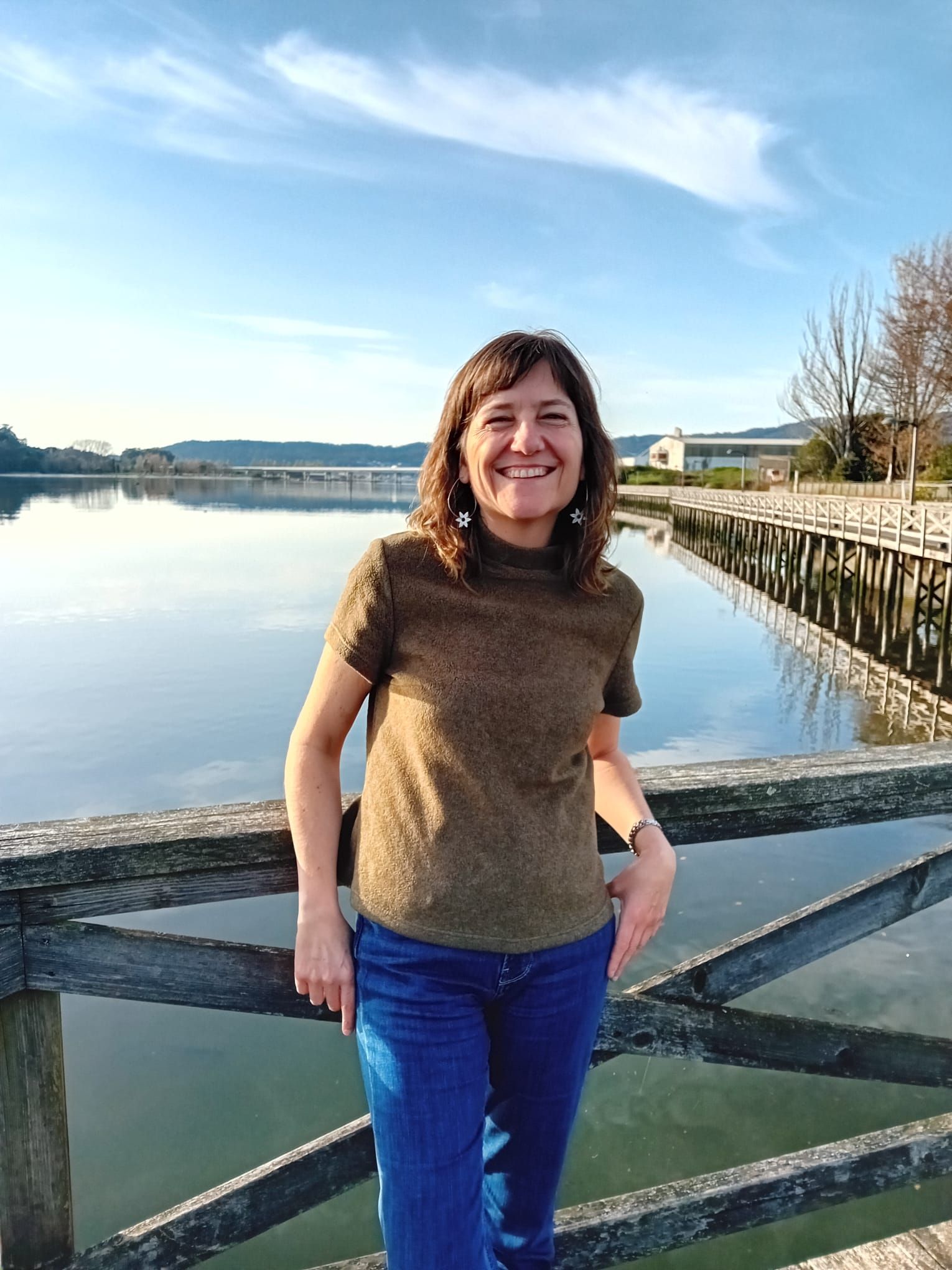 Una mujer está parada en un puente con vistas a un lago.