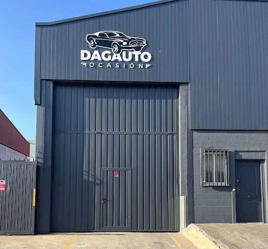 Edificio gris con gran puerta de garaje, cartel