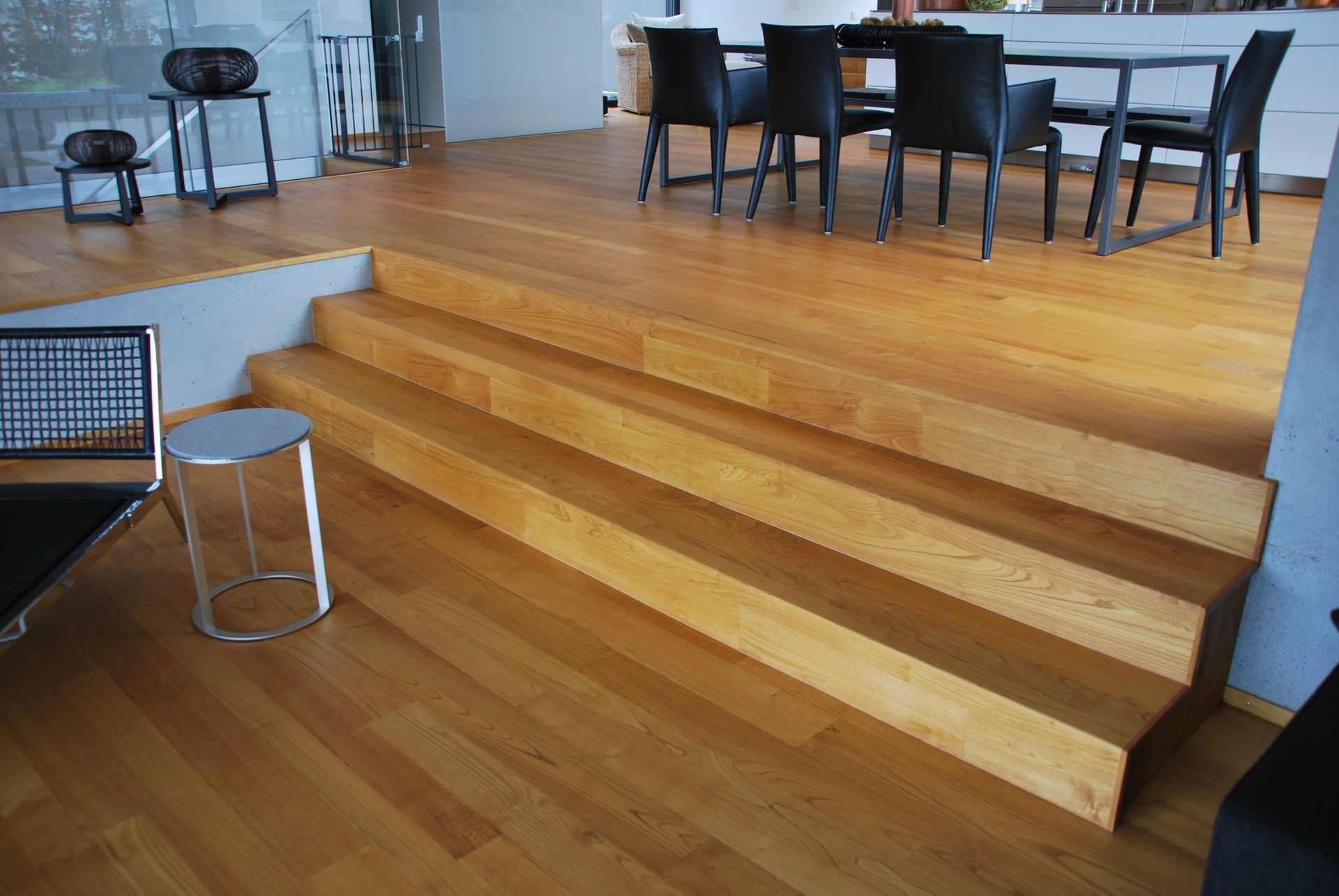 Ein Wohnzimmer mit Couch, Tisch, Treppe und Holzwand. Foto von der Schreinerei Hanselmann GmbH